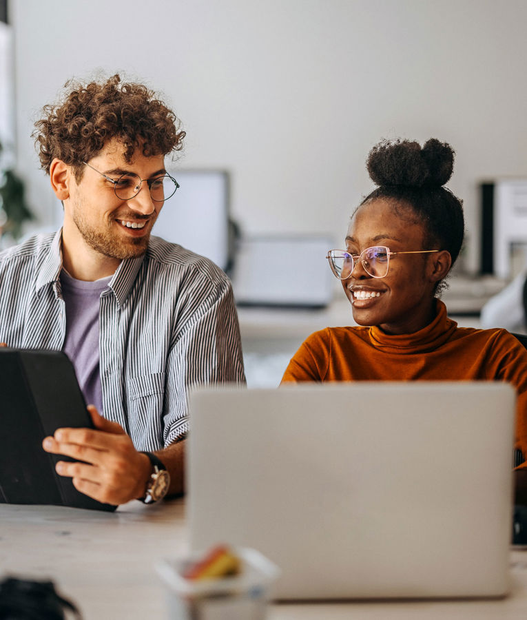 Två kollegor på ett kontor som samarbetar kring arbetsstyrning, schemaläggning och tidsregistrering med hjälp av digitala verktyg