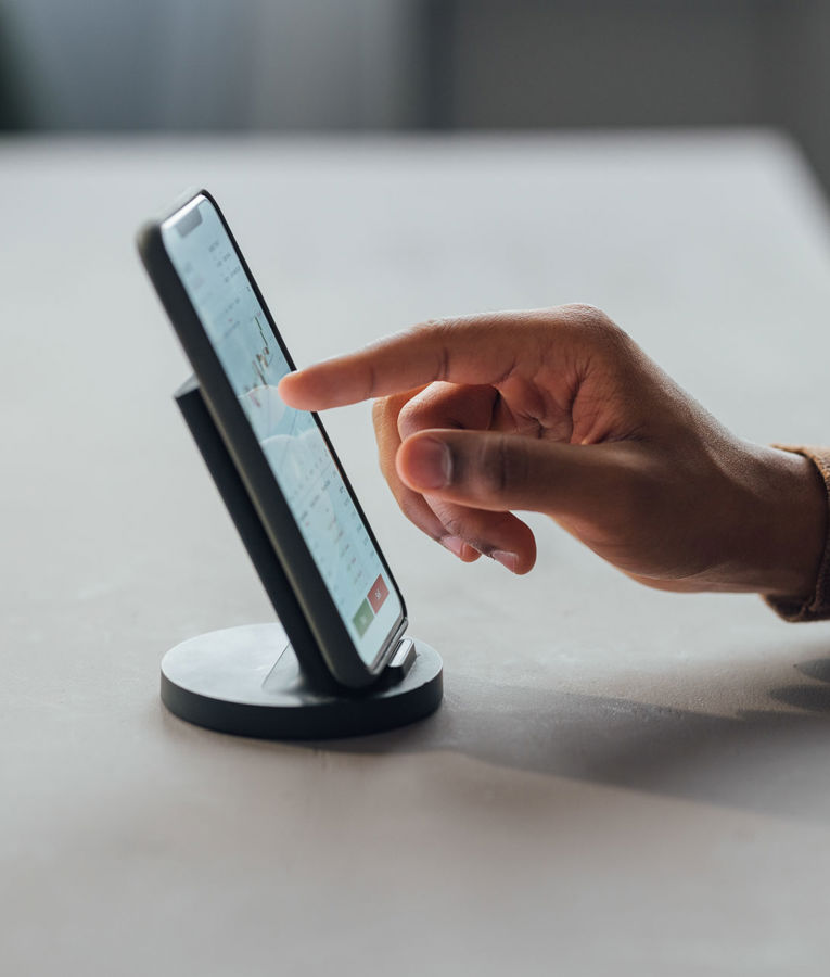 Närbild på en hand som använder en smartphone för arbetsstyrning, schemaläggning och tidsregistrering