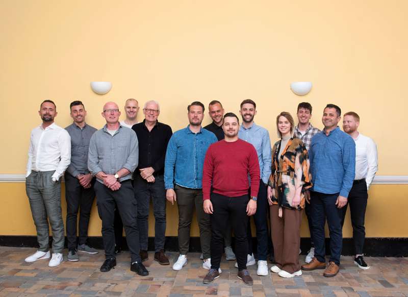Teamfoto av medarbetare som arbetar med workforce management, schemaläggning och tidrapportering för effektiv bemanning och drift.