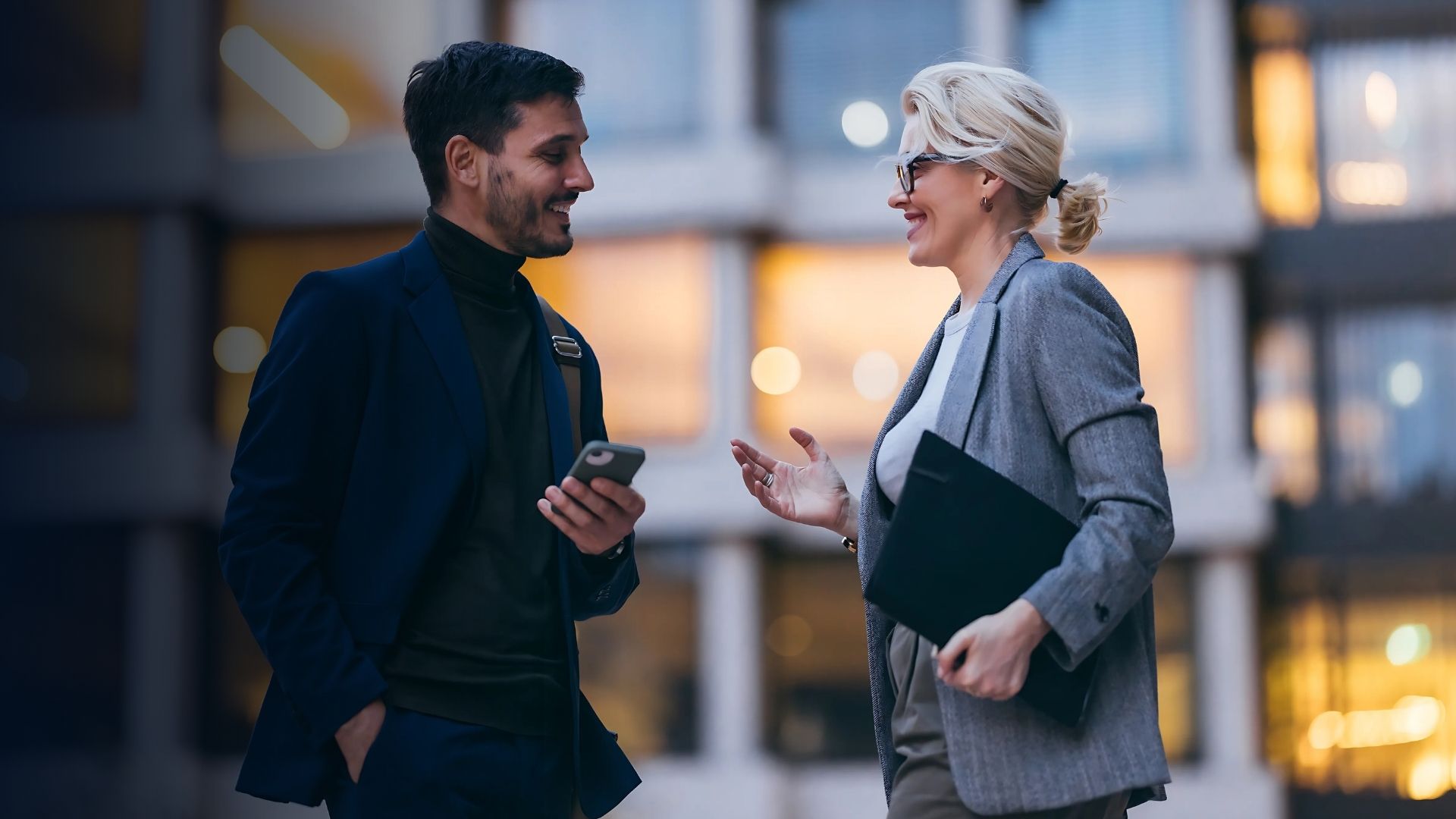 Två kollegor i en affärsmiljö som diskuterar personalplanering och effektiv medarbetarhantering med hjälp av en mobil enhet.