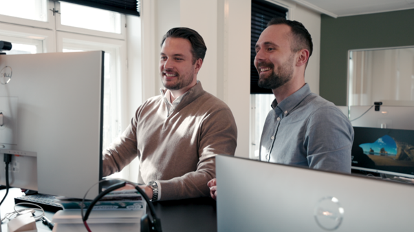 ChatGPT said:  Två kollegor samarbetar framför en datorskärm med digital schemaläggning och tidrapportering i ett modernt workforce management-system.