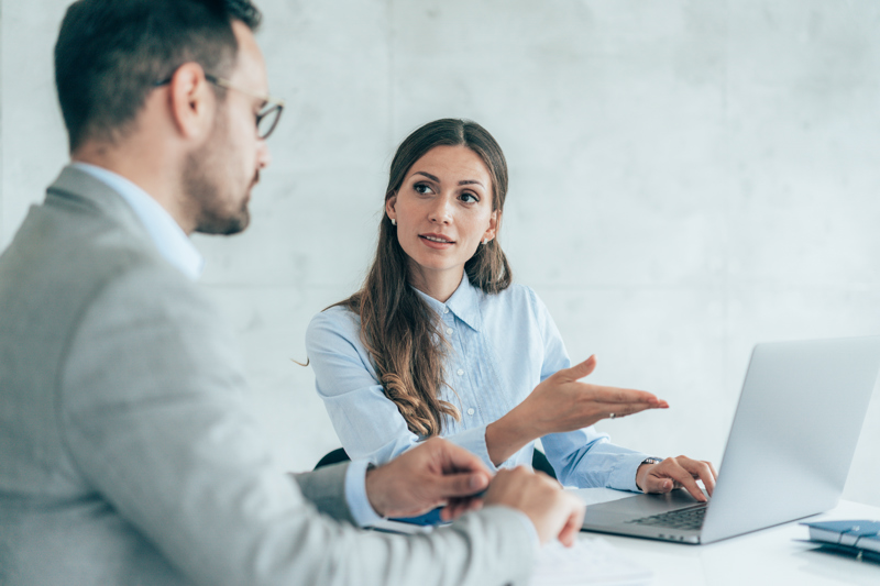 Två kollegor diskuterar AI-baserad workforce management framför en bärbar dator, med fokus på smartare schemaläggning och tidrapportering på arbetsplatsen.