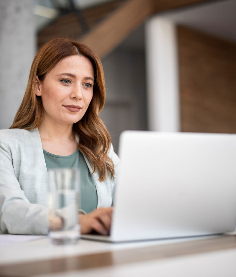 Professionell kvinna som arbetar vid sin bärbara dator, som representerar flexibel arbetsstyrning och datadriven beslutsfattning.