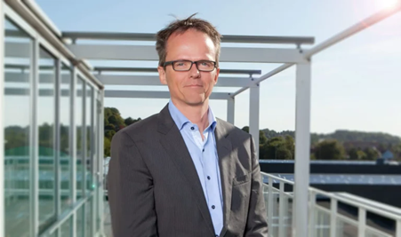 ChatGPT said:  Affärsledare står utomhus framför en kontorsbyggnad och representerar strategisk användning av workforce management, schemaläggning och tidrapportering.